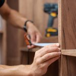 man measuring a wooden closet with a tape measure