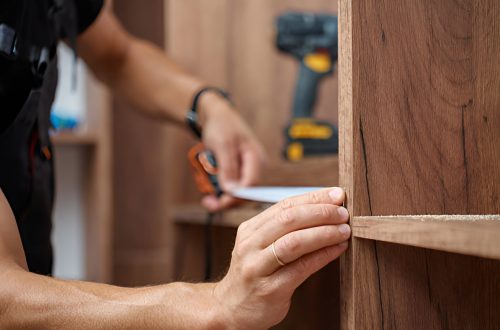 man measuring a wooden closet with a tape measure