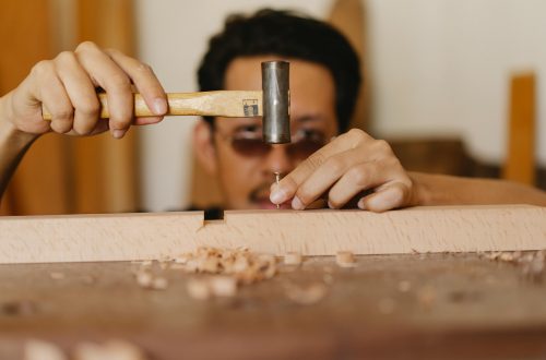 man hammering a nail into wood